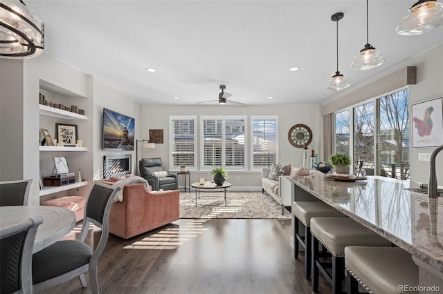 living room with plenty of natural light, dark hardwood / wood-style floors, ceiling fan, and built in shelves