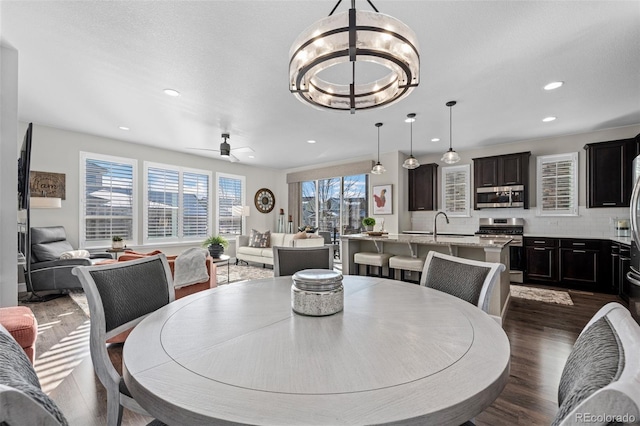 dining space featuring dark wood-type flooring and ceiling fan with notable chandelier