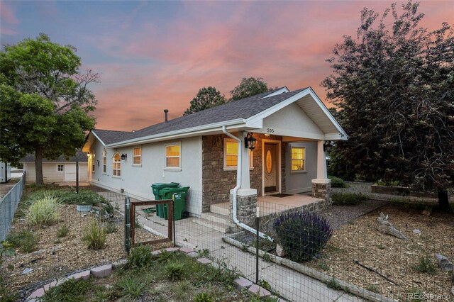 205 Beech St, Hudson, CO 80642 - view of front facade with covered porch, a gate, stone siding, roof with shingles, and stucco siding