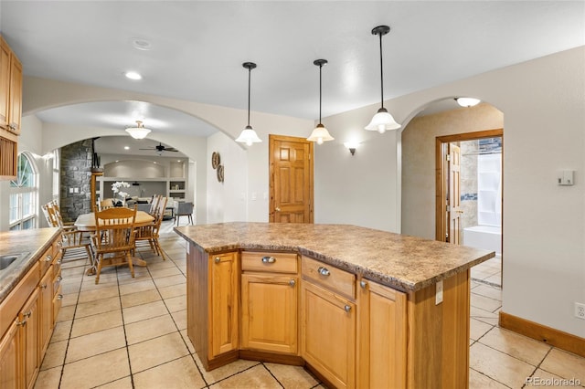 205 Beech St, Hudson, CO 80642 - kitchen featuring arched walkways, a ceiling fan, light tile patterned floors, a kitchen island, and hanging light fixtures