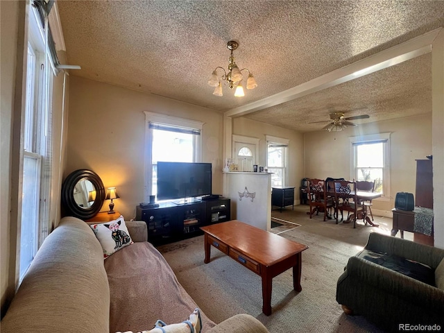 living room with ceiling fan with notable chandelier, carpet floors, and a textured ceiling