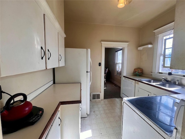 kitchen featuring sink, white cabinets, and white appliances