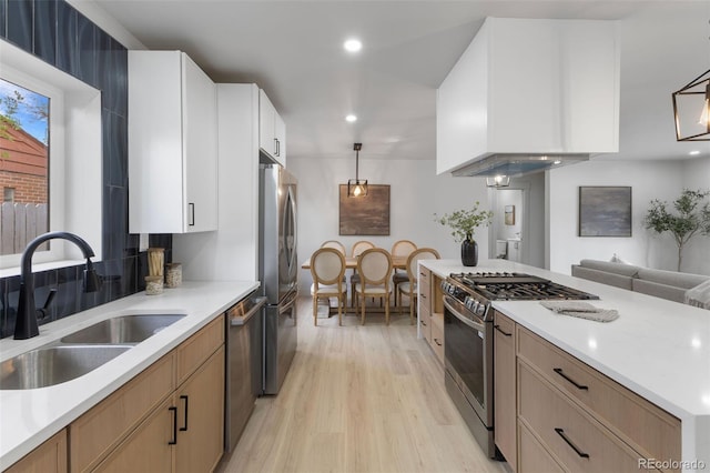 kitchen featuring light countertops, stainless steel appliances, a sink, and light wood finished floors