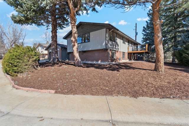 view of property exterior with brick siding and a wooden deck