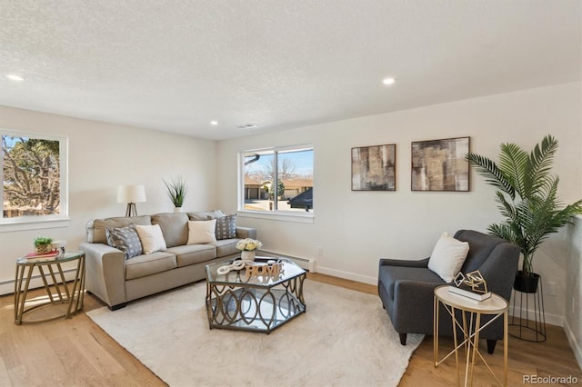 living room featuring a baseboard heating unit, recessed lighting, a textured ceiling, and wood finished floors