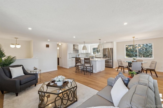 living room with light wood-style flooring, a chandelier, and recessed lighting