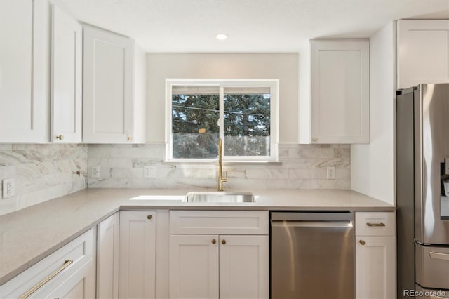 kitchen with a sink, white cabinets, light countertops, appliances with stainless steel finishes, and decorative backsplash