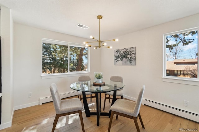 dining area featuring a notable chandelier, a baseboard heating unit, wood finished floors, visible vents, and baseboards