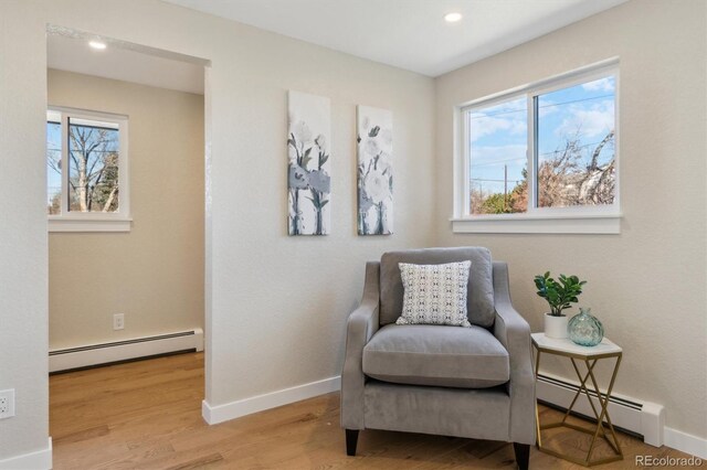 living area featuring a baseboard heating unit, plenty of natural light, and wood finished floors