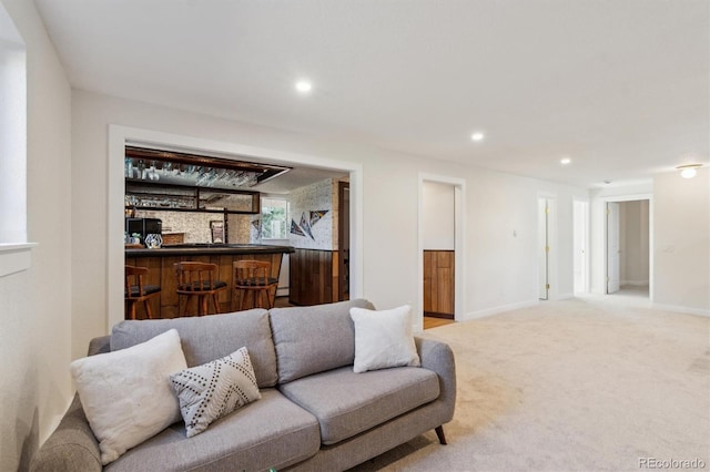 carpeted living room featuring recessed lighting, bar area, and baseboards