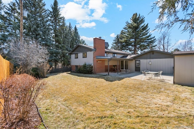 back of house featuring a patio area, fence, a chimney, and a lawn