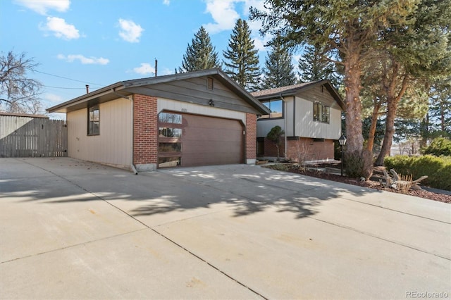 view of front of property featuring brick siding, fence, and driveway