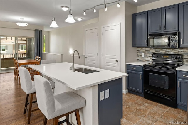 837 E 98th Ave Unit 405, Thornton, CO 80229 - kitchen featuring black appliances, a kitchen bar, decorative backsplash, light countertops, and a center island with sink