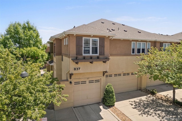 837 E 98th Ave Unit 405, Thornton, CO 80229 - view of front facade with an attached garage, concrete driveway, stucco siding, and a shingled roof
