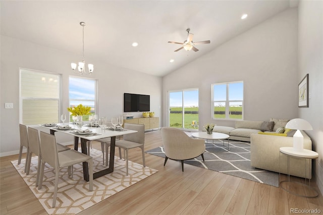 living area featuring baseboards, high vaulted ceiling, recessed lighting, light wood-style floors, and ceiling fan with notable chandelier