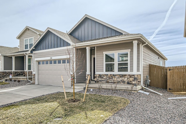 view of front of property with board and batten siding, fence, covered porch, stone siding, and driveway