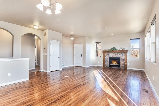 unfurnished living room featuring a fireplace, hardwood / wood-style floors, and an inviting chandelier