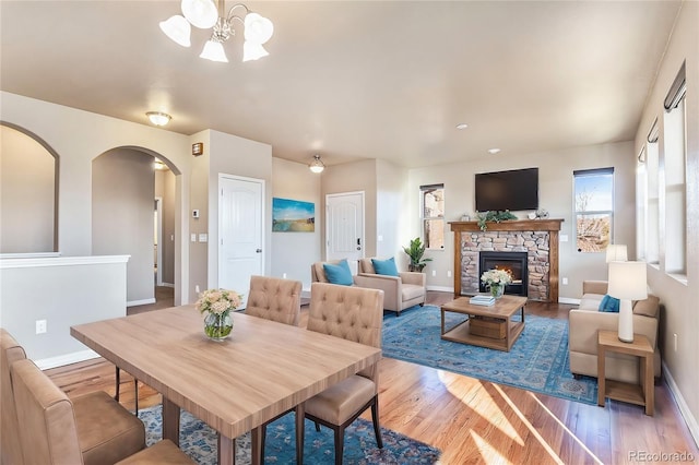 dining room with hardwood / wood-style flooring, a fireplace, and a notable chandelier