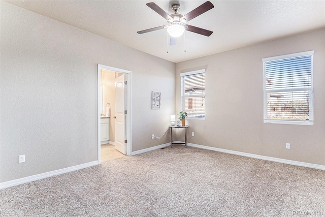 unfurnished bedroom with light colored carpet, ensuite bath, and ceiling fan