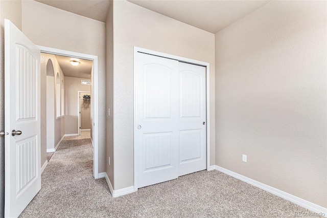 unfurnished bedroom featuring light carpet and a closet