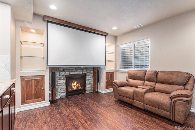 living room featuring a textured ceiling, built in shelves, a fireplace, and dark hardwood / wood-style floors