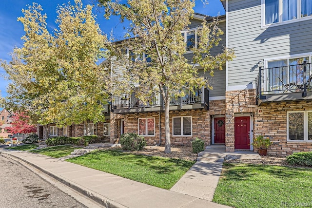 multi unit property featuring a front lawn and a balcony