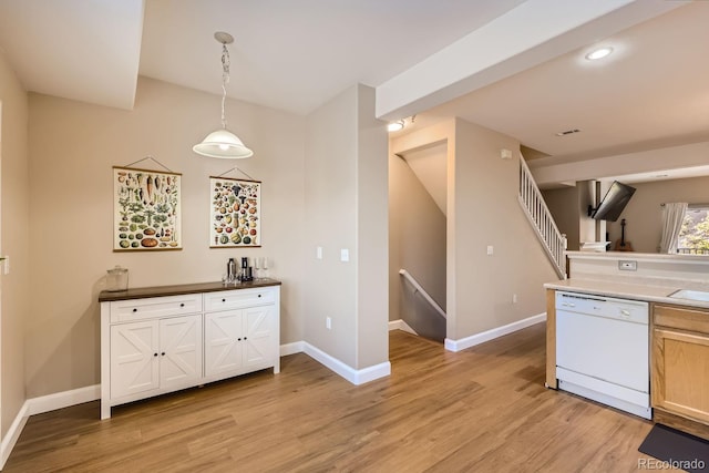 kitchen with light hardwood / wood-style floors, dishwasher, and hanging light fixtures