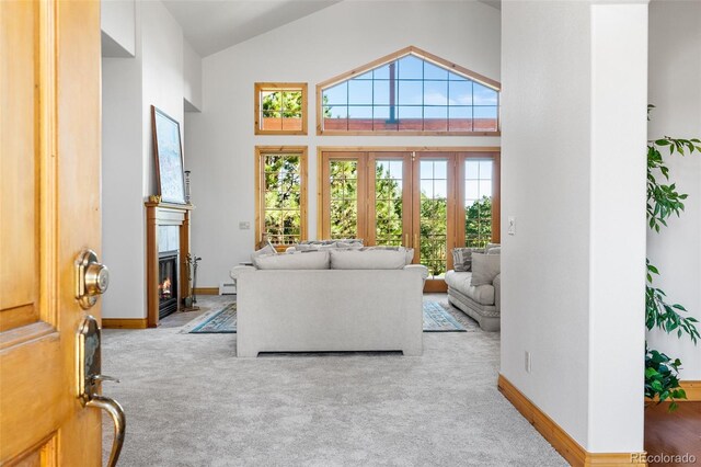 living room with high vaulted ceiling, carpet floors, and a baseboard heating unit