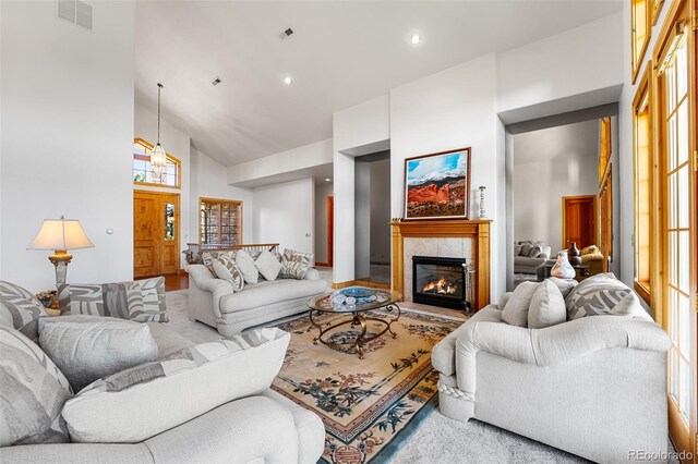 living room with high vaulted ceiling, a wealth of natural light, and a tile fireplace