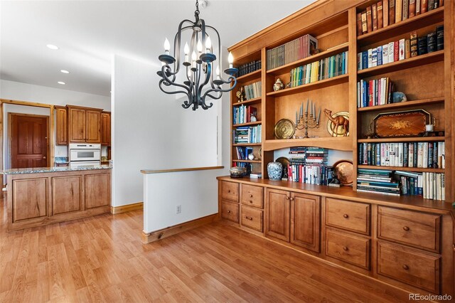 interior space featuring white oven, hardwood / wood-style floors, and an inviting chandelier