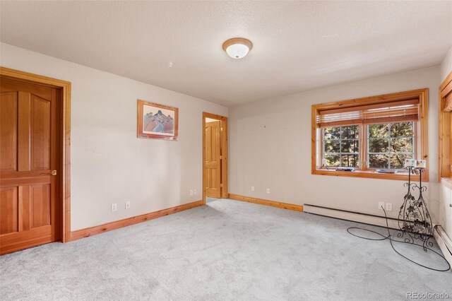 carpeted empty room featuring a baseboard radiator and a textured ceiling