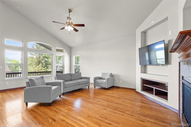 1513 Cannon Mountain Dr, Longmont, CO 80503 - living area featuring a glass covered fireplace, light wood finished floors, ceiling fan, high vaulted ceiling, and plenty of natural light