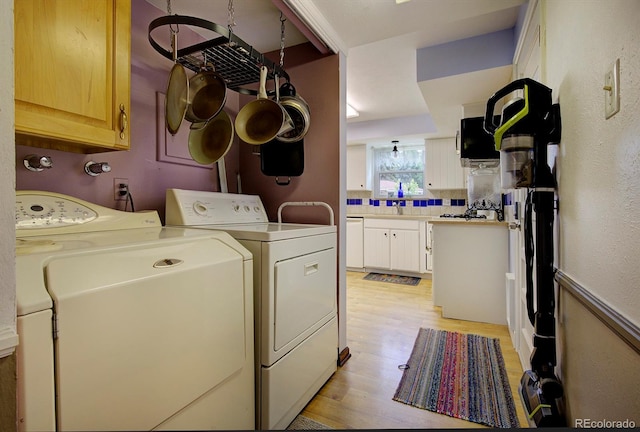 10373 W 75th Ave, Arvada, CO 80005 - laundry room featuring independent washer and dryer, light wood-type flooring, and cabinet space