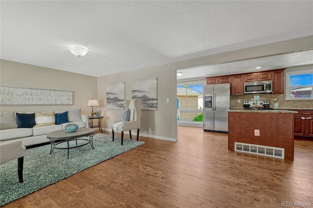 living area with a textured ceiling, wood finished floors, and baseboards