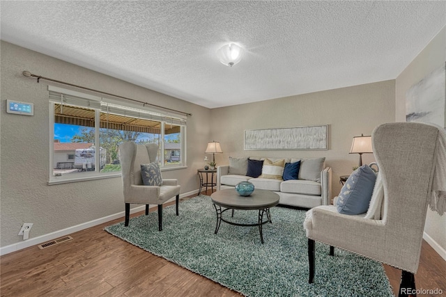 living room with wood finished floors, baseboards, a textured ceiling, and a textured wall
