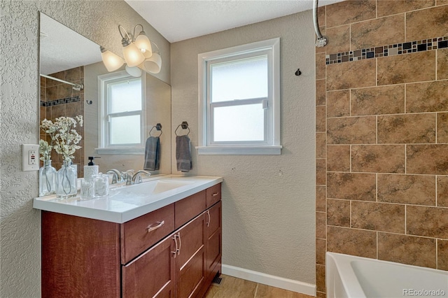 bathroom featuring a textured wall, healthy amount of natural light, vanity, shower / bath combination, and a textured ceiling
