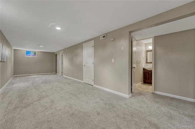 finished basement with light carpet, a textured wall, and baseboards