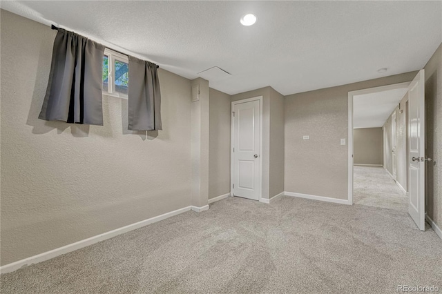 unfurnished bedroom featuring baseboards, light carpet, and a textured wall