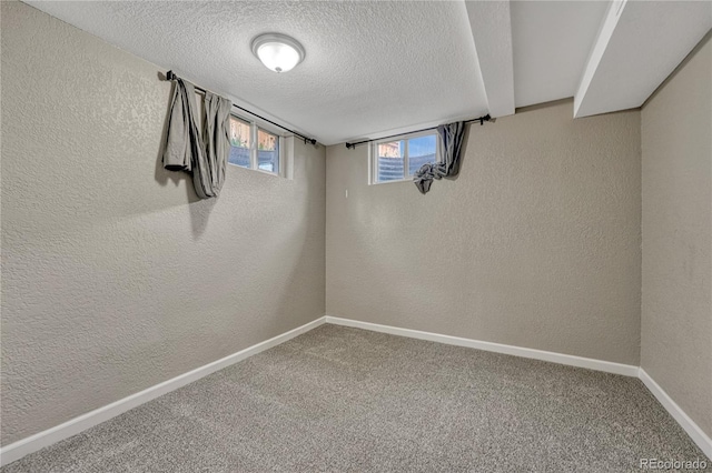 below grade area featuring a textured wall, a textured ceiling, baseboards, and carpet floors