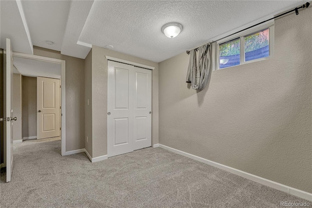 unfurnished bedroom featuring a textured wall, a textured ceiling, carpet floors, baseboards, and a closet