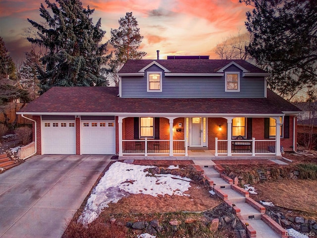 view of front of house featuring covered porch, driveway, brick siding, and a garage