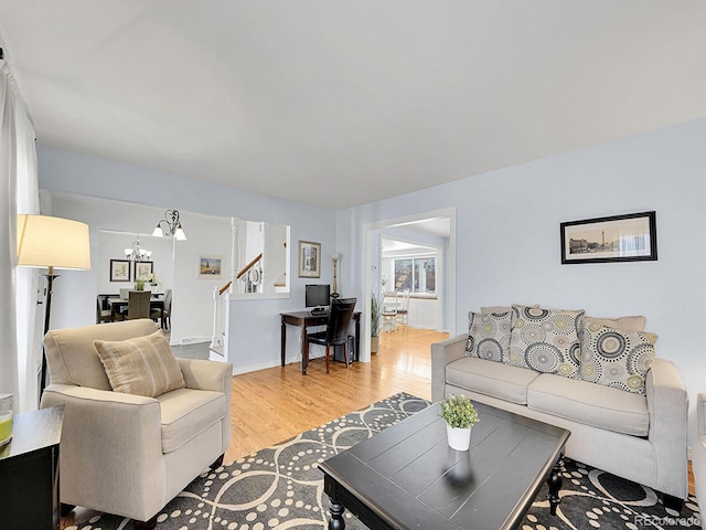 living area featuring light wood finished floors, baseboards, stairway, and a chandelier