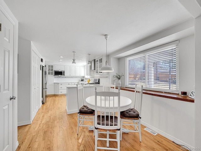 dining area featuring baseboards, visible vents, and light wood-style floors