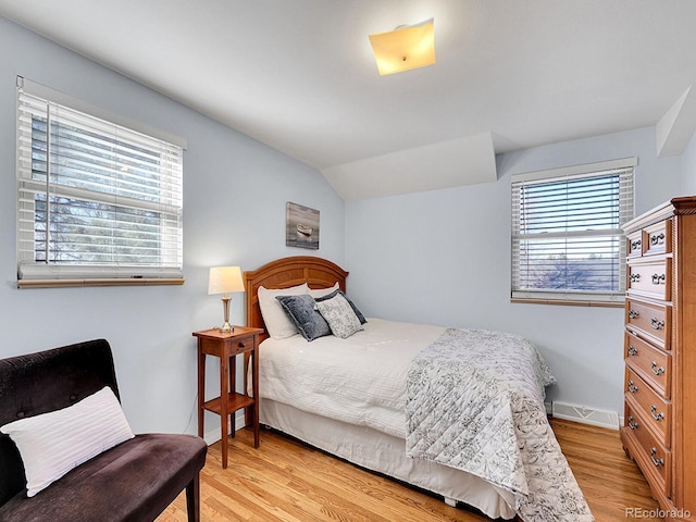 bedroom featuring light wood-style flooring, visible vents, baseboards, and vaulted ceiling