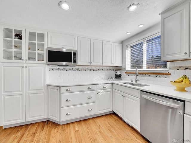 kitchen featuring a sink, white cabinets, light countertops, appliances with stainless steel finishes, and light wood-type flooring