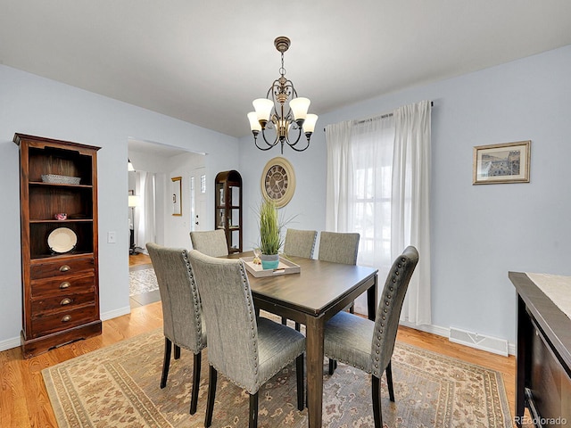 dining area with an inviting chandelier, light wood-style flooring, visible vents, and baseboards