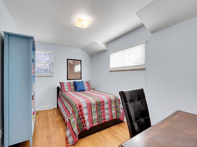 bedroom featuring visible vents, vaulted ceiling, baseboards, and wood finished floors