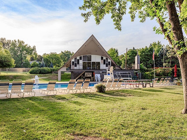 back of property with stairway, an outdoor pool, a patio, and a yard