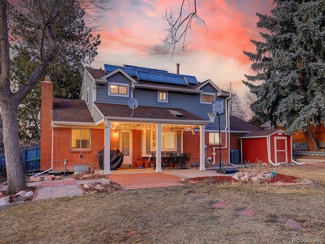 rear view of property featuring a patio area, brick siding, an outdoor structure, and a storage unit