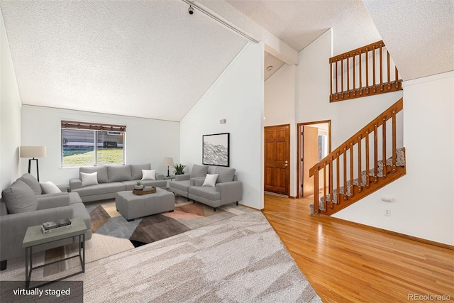 living room with a textured ceiling, wood-type flooring, and high vaulted ceiling